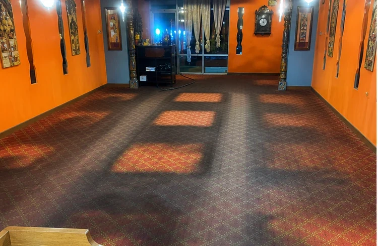 Red patterned carpet with dark areas in an orange-walled commercial space in Bel Air